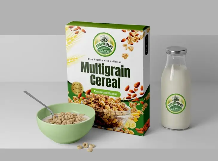 Box of Greenfields Multigrain Cereal with almond and banana flavor, a green bowl of cereal with a spoon, and a glass bottle of milk on a gray surface.