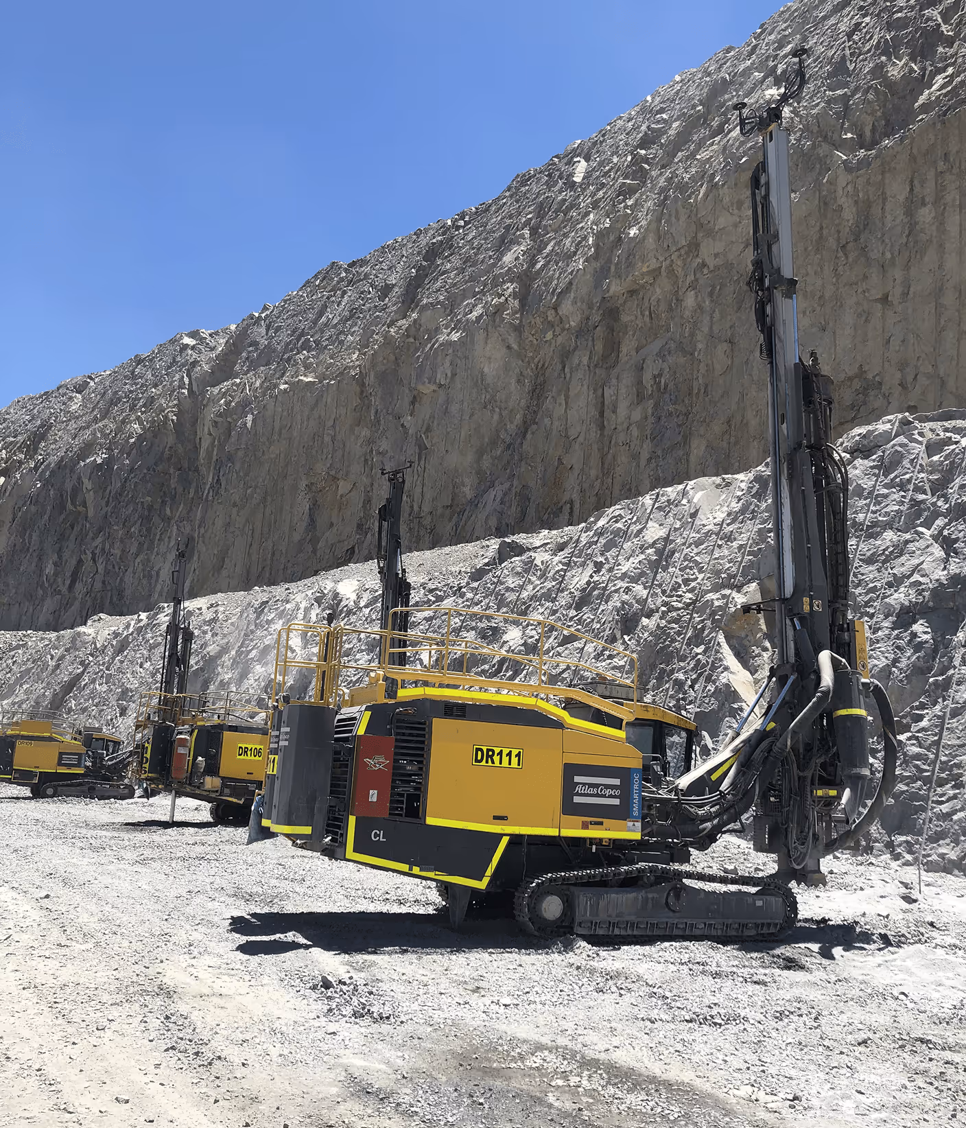 CAT excavator drilling equipment at quarry site - heavy machinery operating in mining environment with rock face
