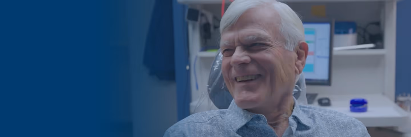 Smiling elderly man sitting in a dental chair in a clinic.