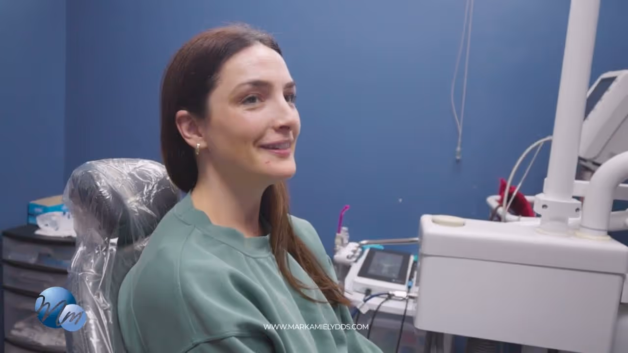 Smiling woman with brown hair sitting in a dental chair in a dental office.