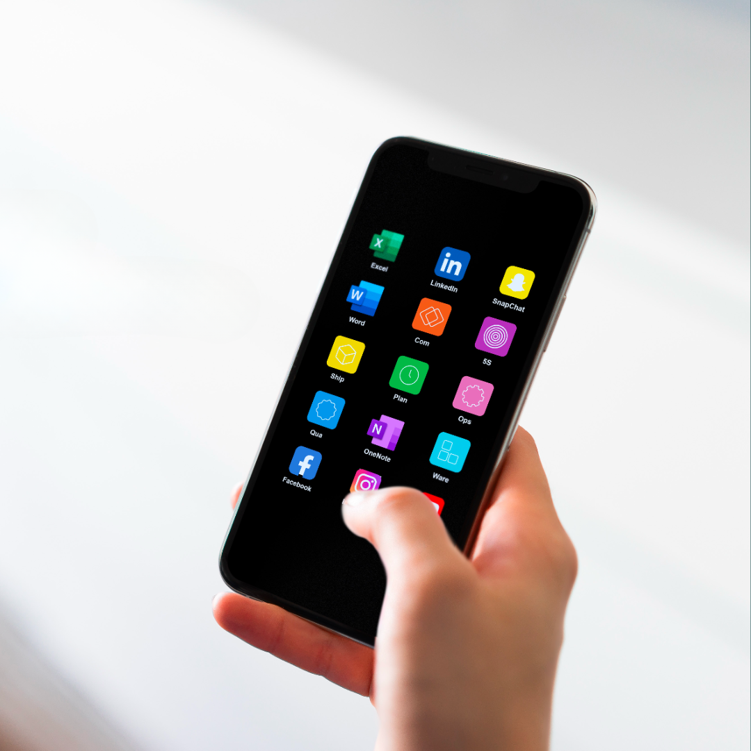 Hand holding smartphone displaying a grid of colorful app icons including Excel, LinkedIn, Snapchat, Word, Facebook, and Instagram on a black screen.