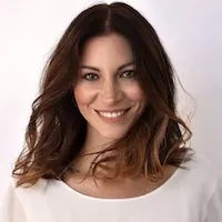 Porträt von dr. dr. Maja Grahovac (Führende Fachärztin für Haut- und Geschlechtskrankheiten) mit langen braunen Haaren und weißem Oberteil, die lächelt.