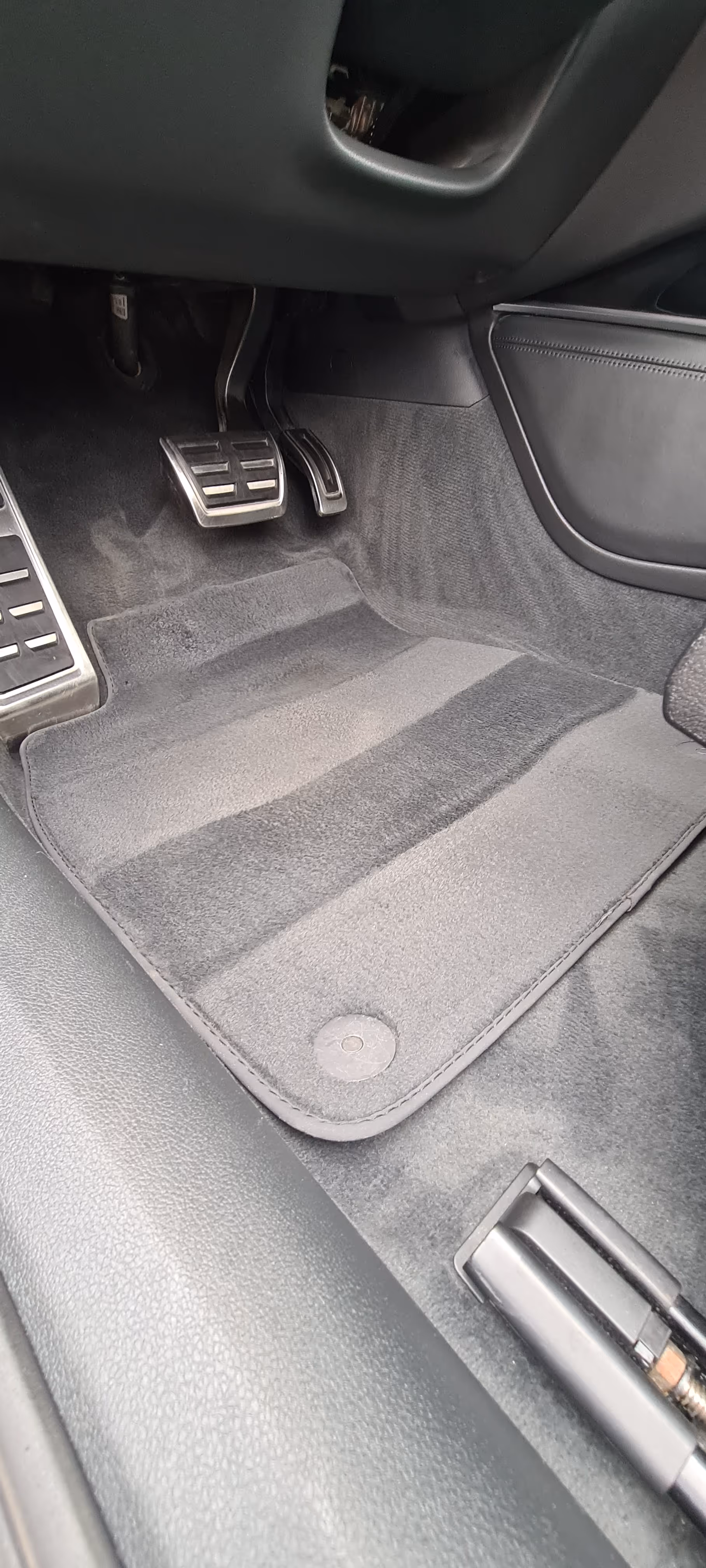 Bilens fodrum viser speeder, bremse og fodbjælke pedaler med et rent sort gulvtæppe