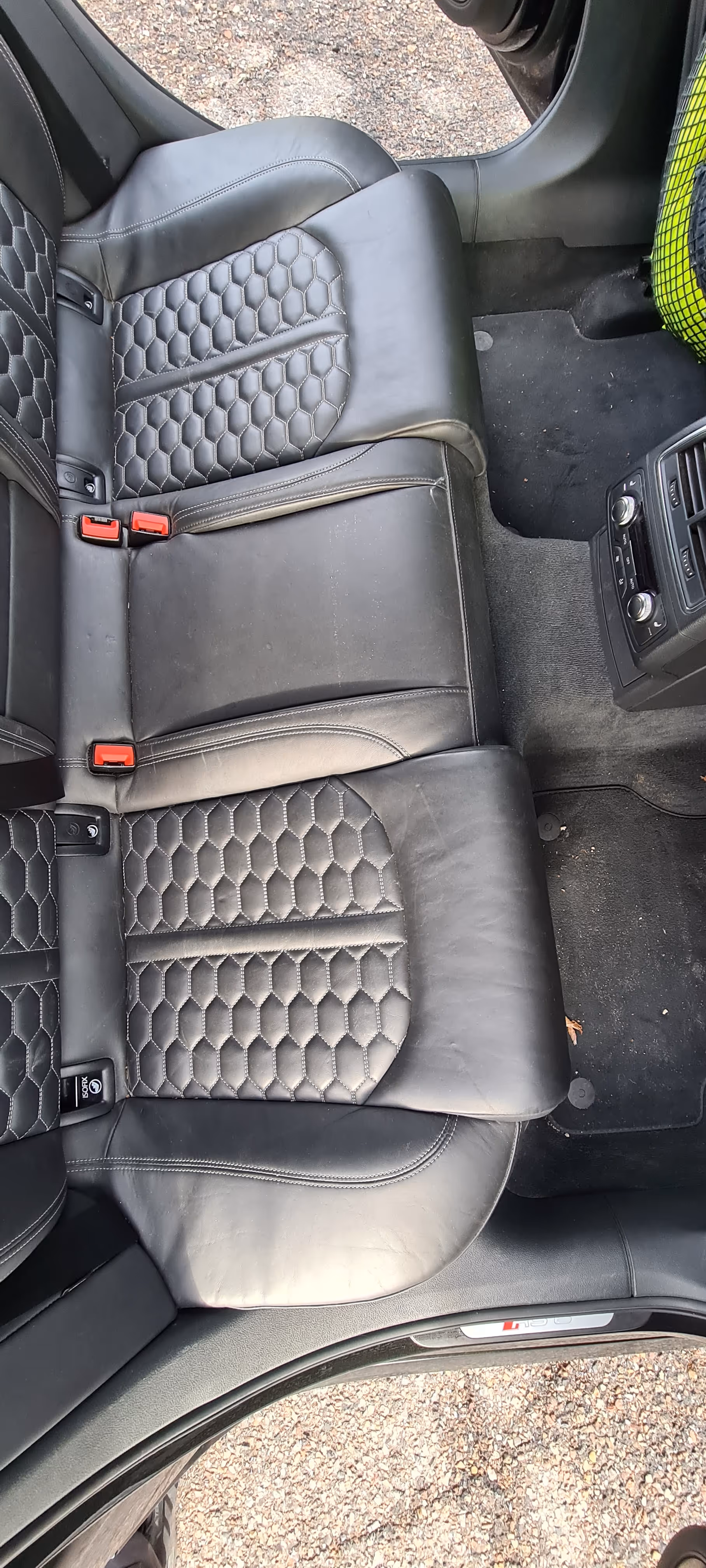 Beskidte sorte læder bagsæder med sekskantet syningmønster og synlige bageste luftventiler på midterkonsollen