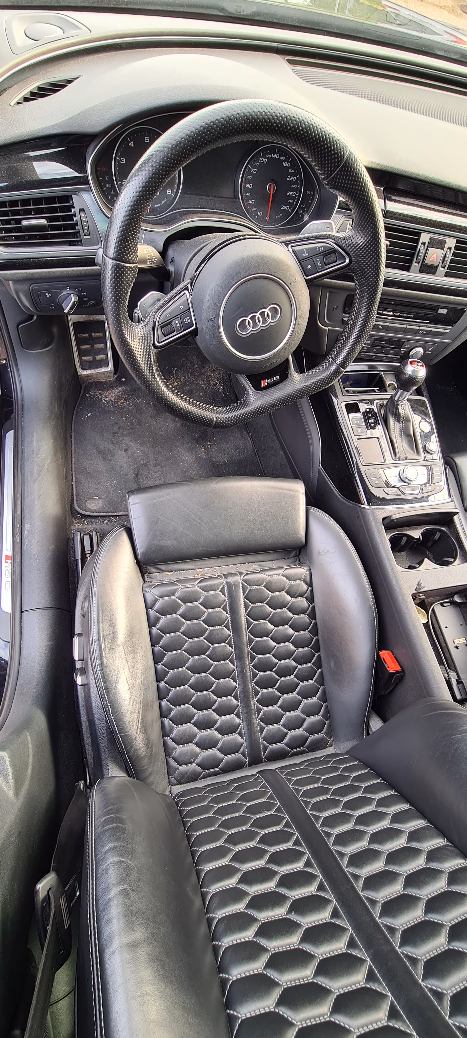 Beskidt Audi inderside med sort perforeret læder rattet, beskidt sekskantet læder førersæde, gearstang og instrumentbræt