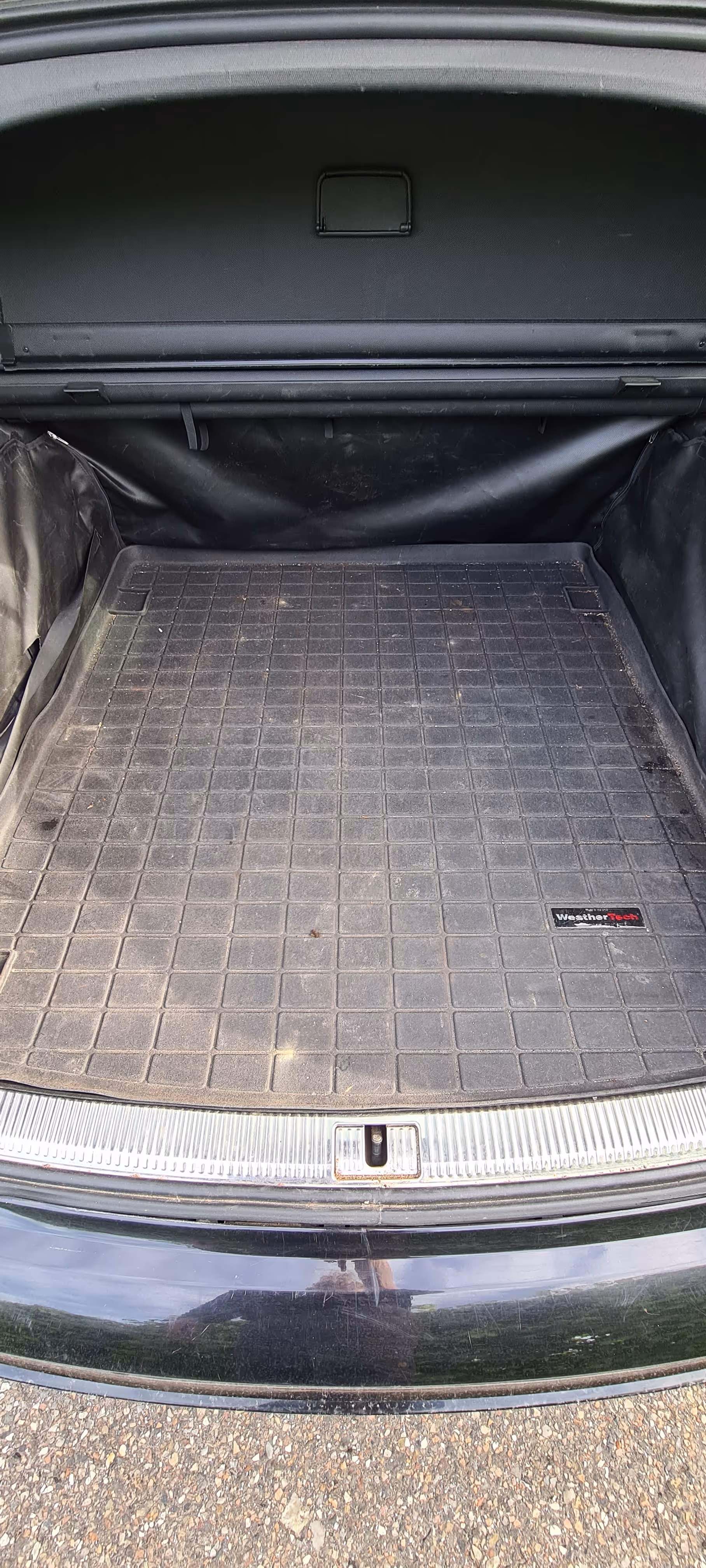 Tom bil bagagerum med et sort WeatherTech gummi lasttæppe og lidt snavs på tæppet og det omkringliggende område