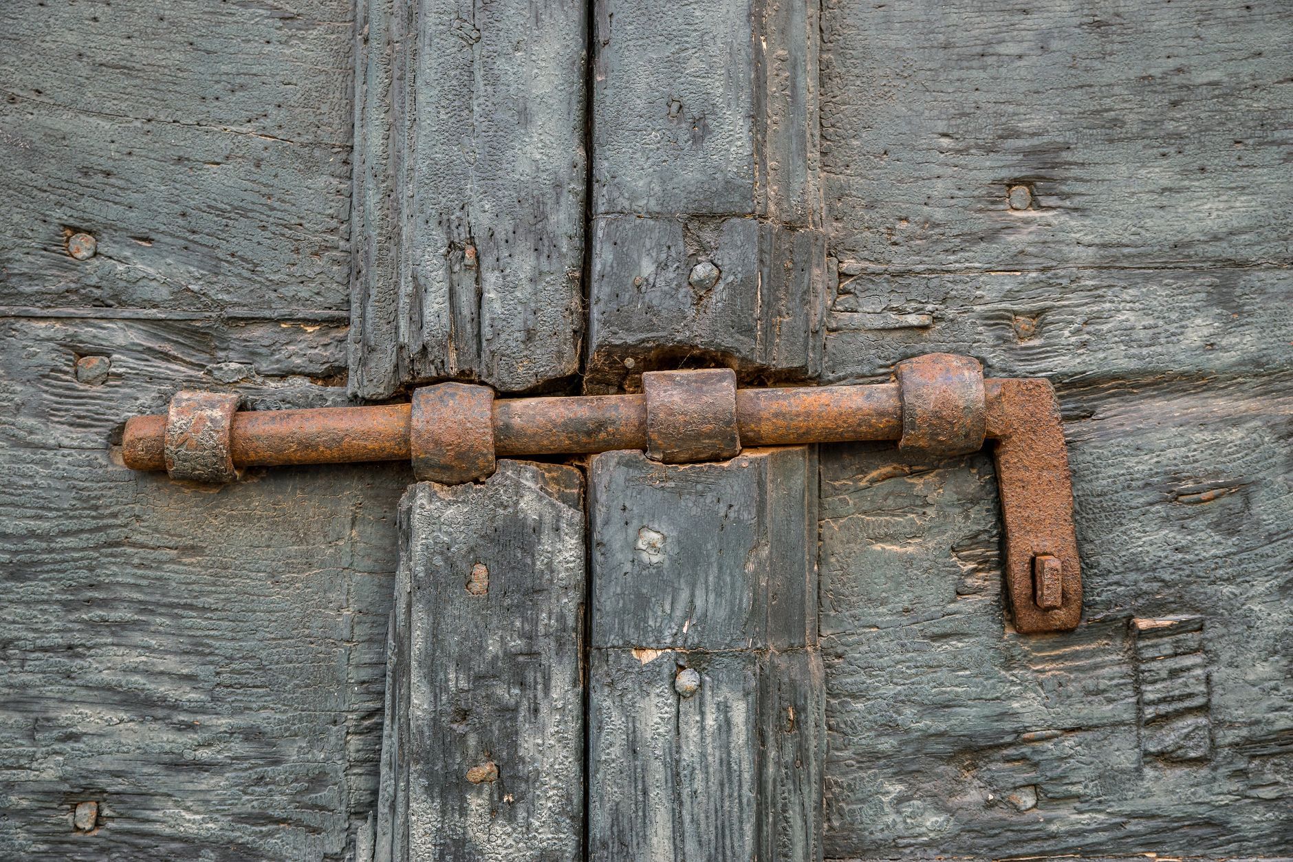 Gros plan sur une charnière de porte rouillée et endommagée causant un défaut de fermeture