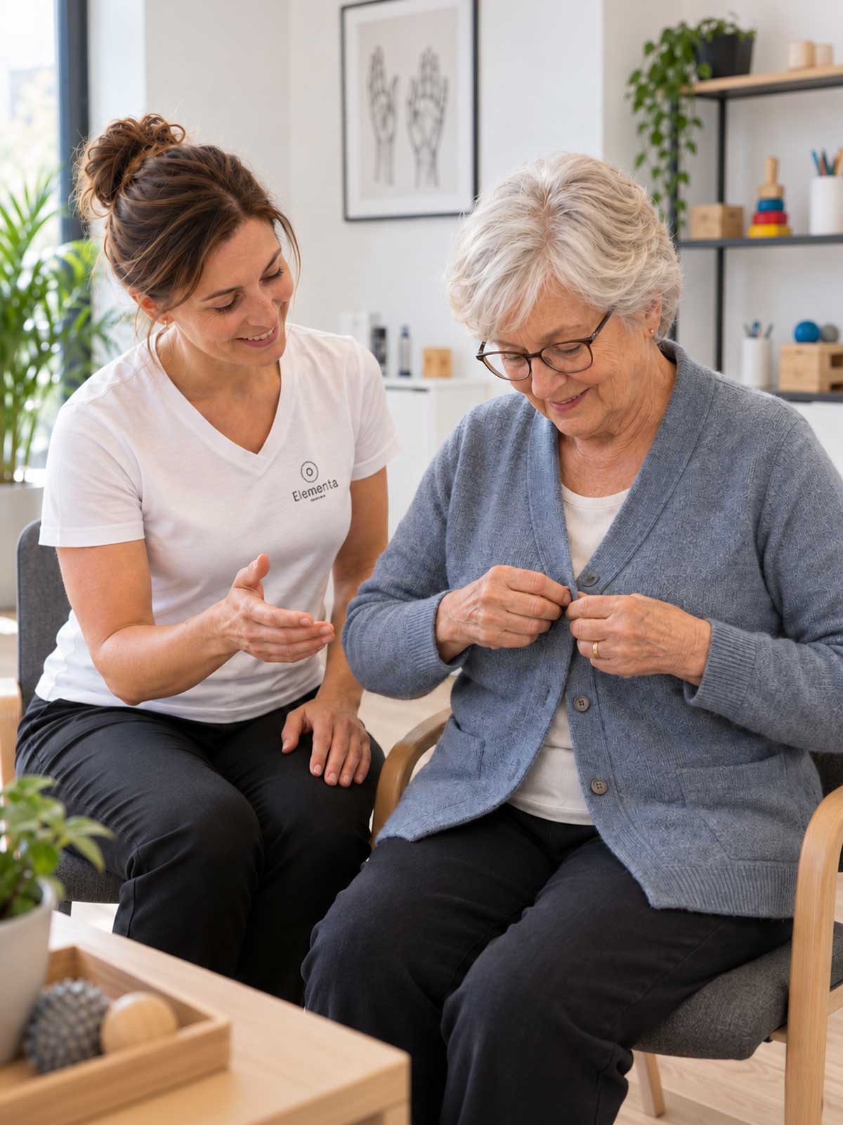 Seniorin übt mit einer Ergotherapeutin das Schließen ihrer Strickjacke