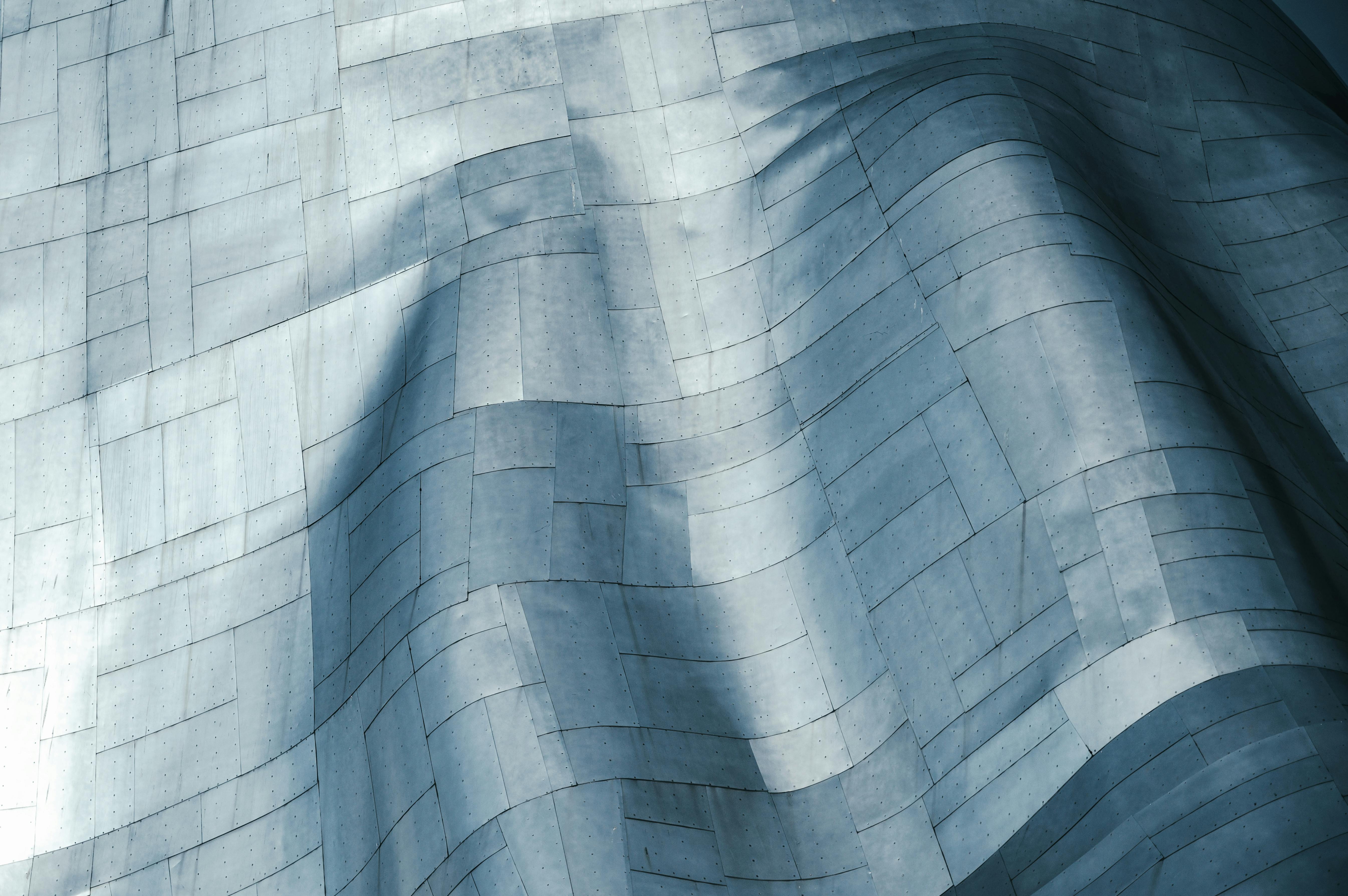 Curved metallic wall composed of large, overlapping steel panels with rivets.