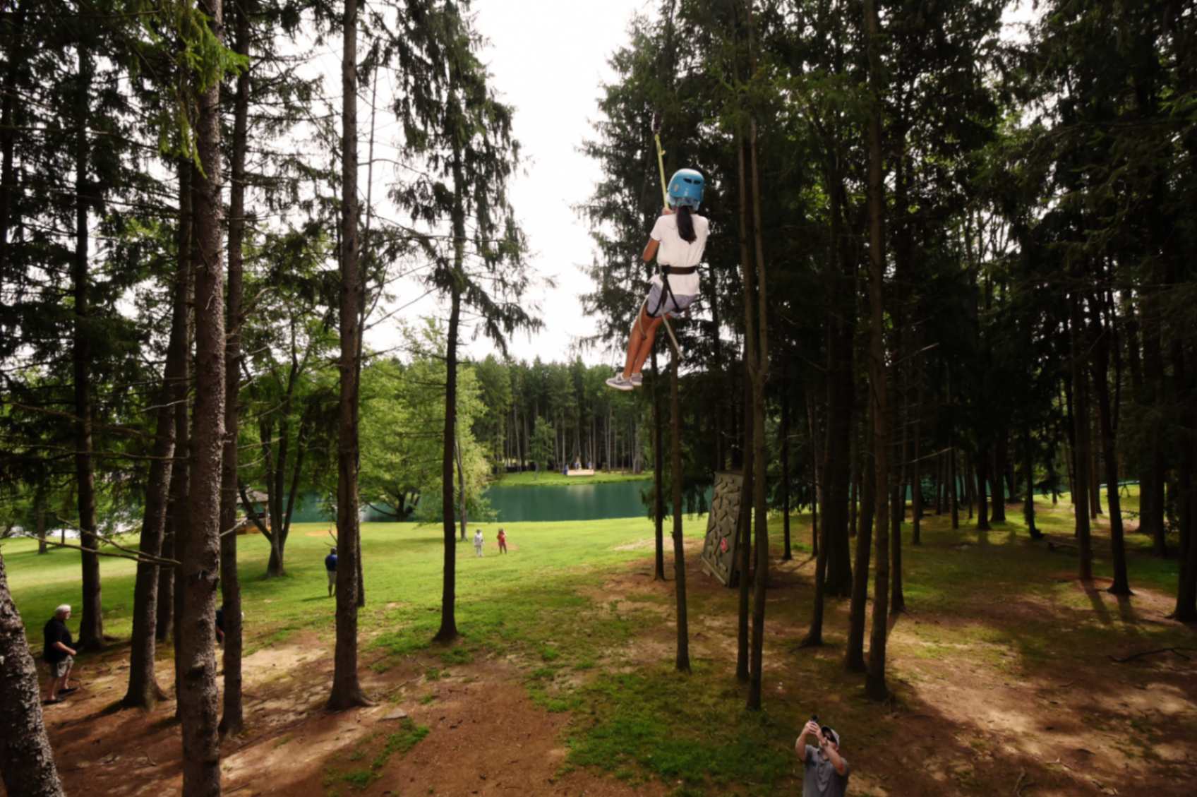 Guest riding a zipline through the trees at Frogbridge, overlooking the lake
