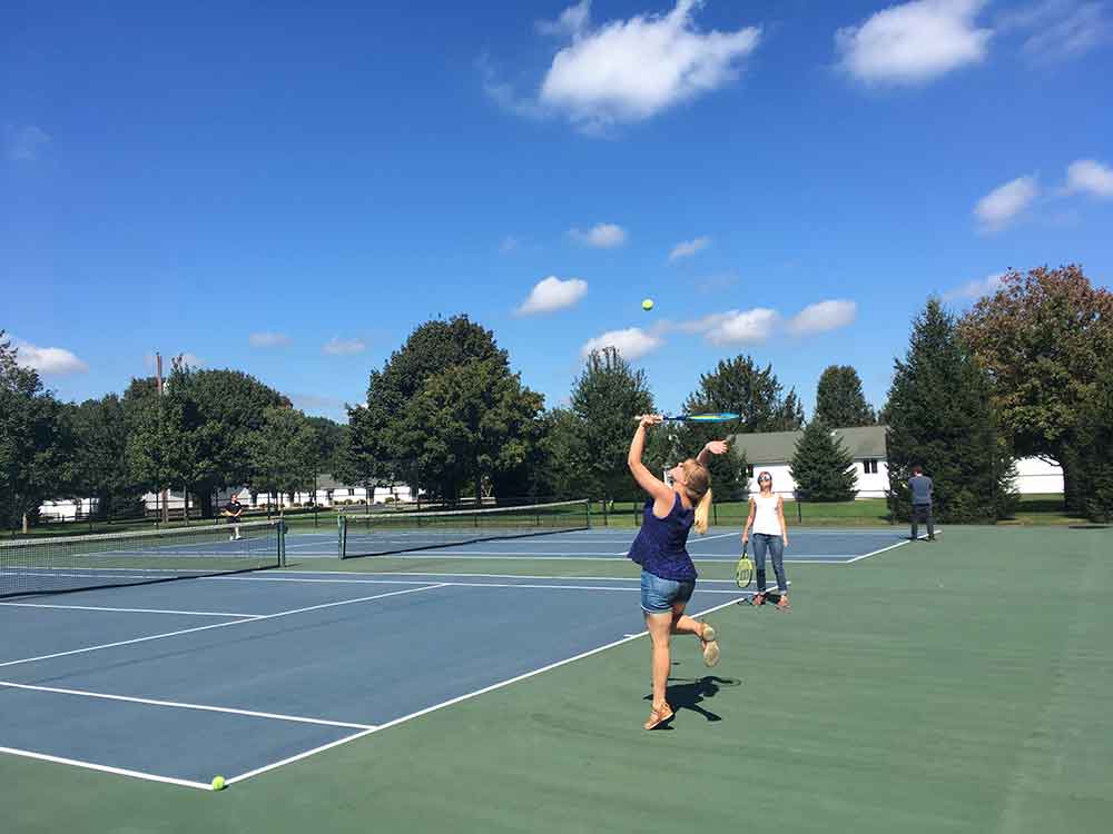 Woman serving the ball on one of Frogbridge's outdoor tennis courts