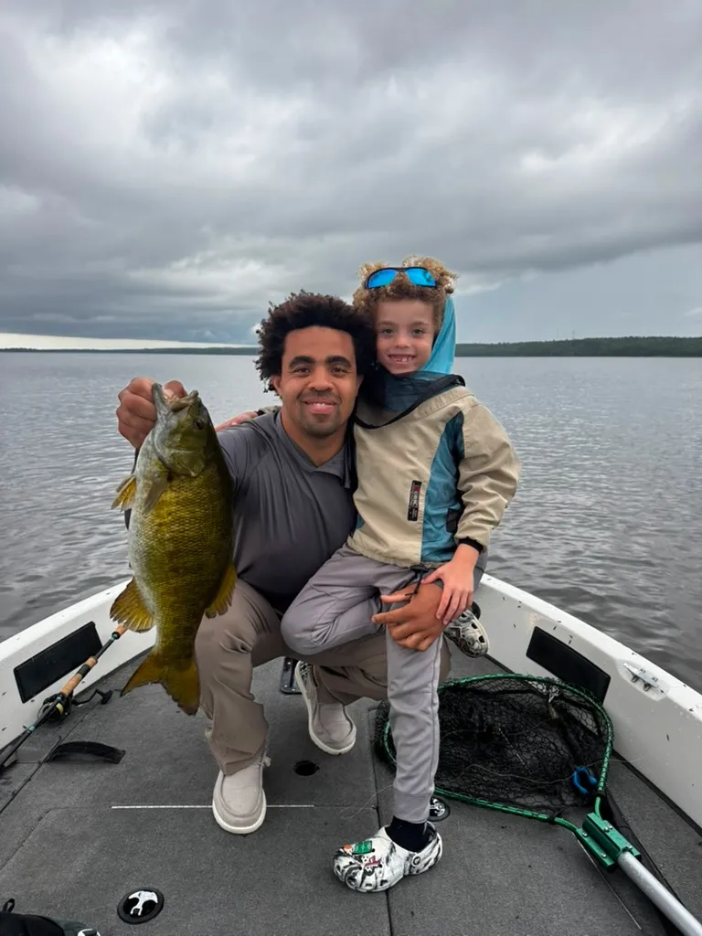 Father and young son holding a smallmouth bass in a boat