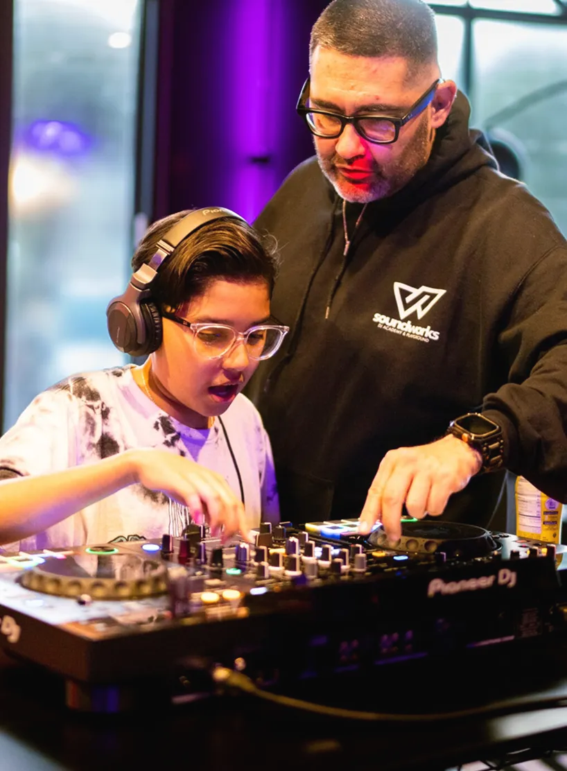 Instructor teaching a young student on DJ equipment
