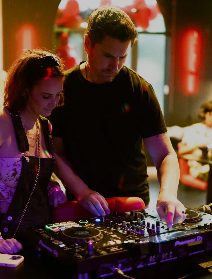 Two people learning DJ controls together