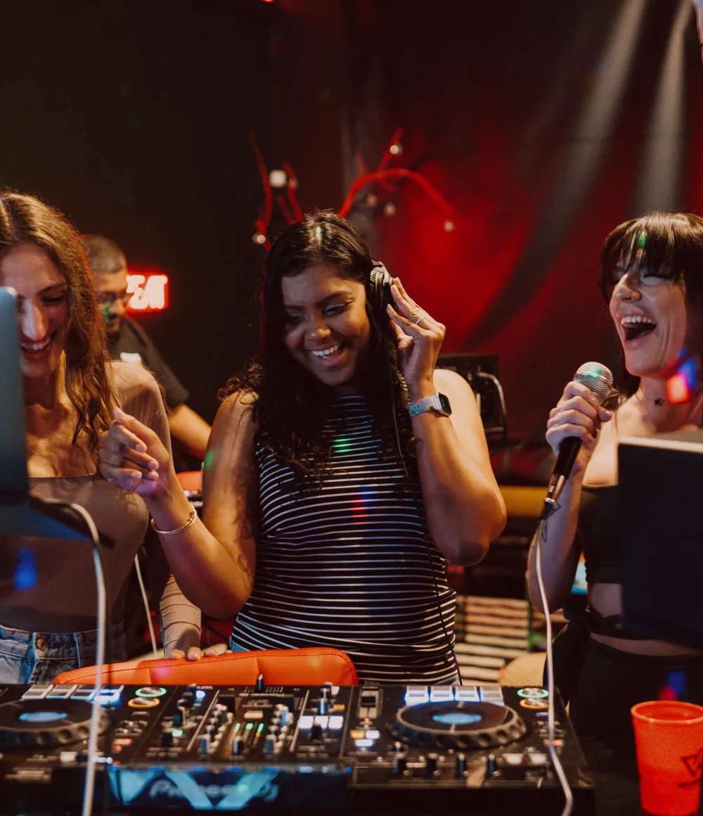 Group laughing and singing around a DJ booth