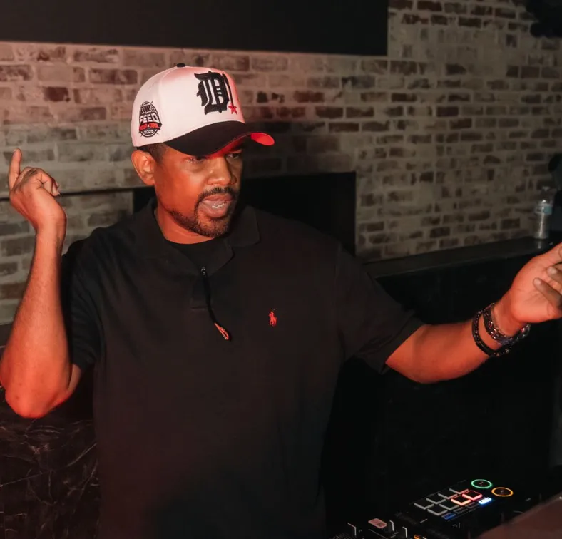 DJ gesturing with one hand while mixing music