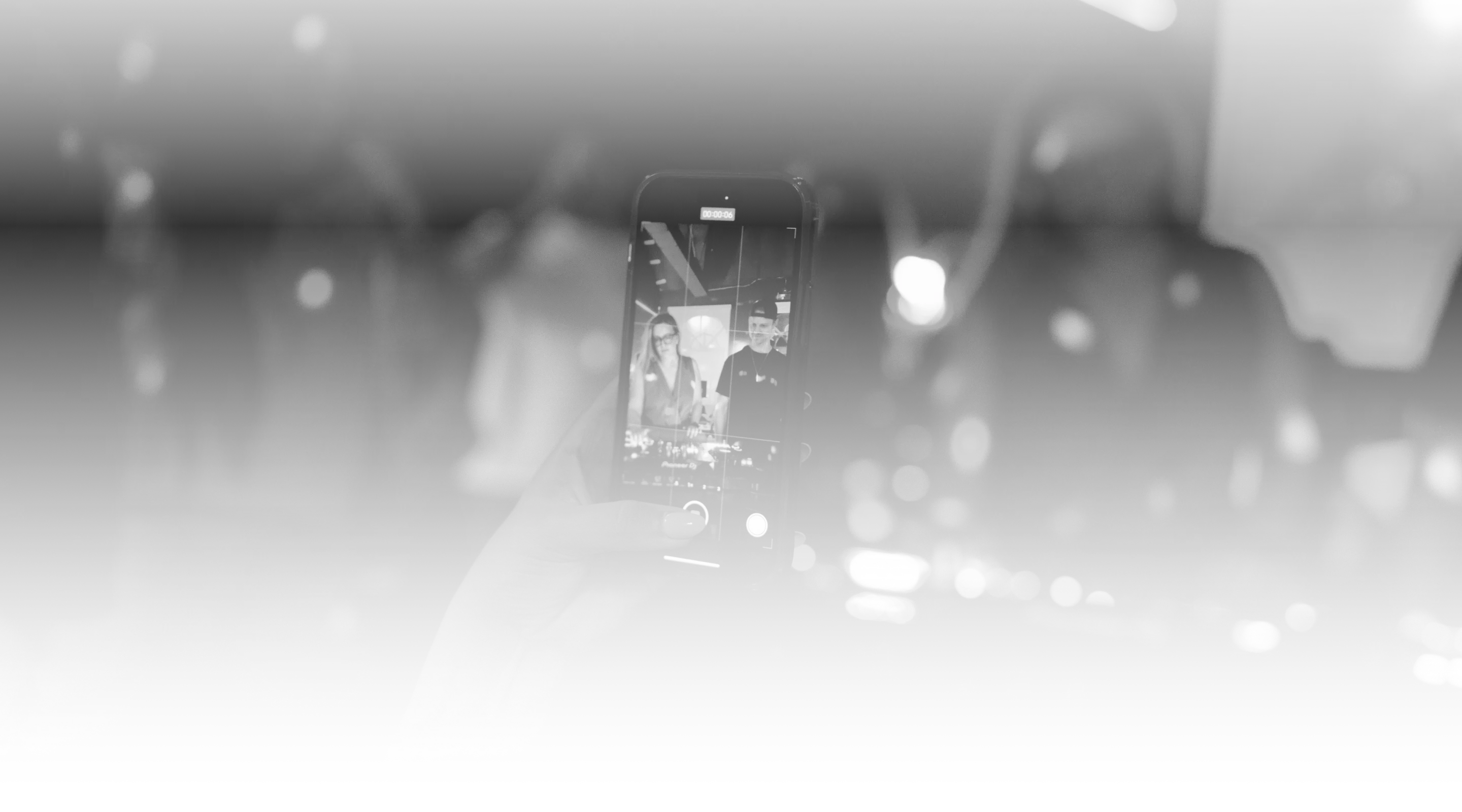 Person recording DJs performing on a smartphone
