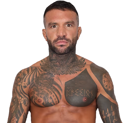 Muscular man with short dark hair and a beard, shirtless with extensive black and gray tattoos covering his chest, neck, and arms.