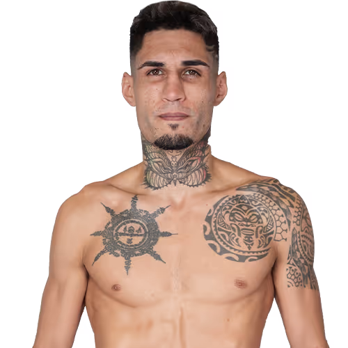 Shirtless man with short dark hair and a goatee, displaying intricate tribal tattoos on his neck, left shoulder, and upper chest.