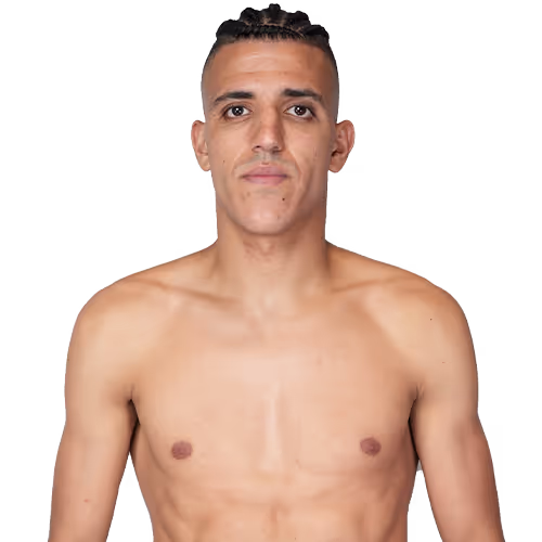 Shirtless young man with short braided hair, standing and facing forward.