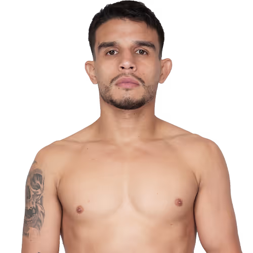 Shirtless man with a tattoo on his left upper arm and short dark hair, facing forward with a neutral expression.