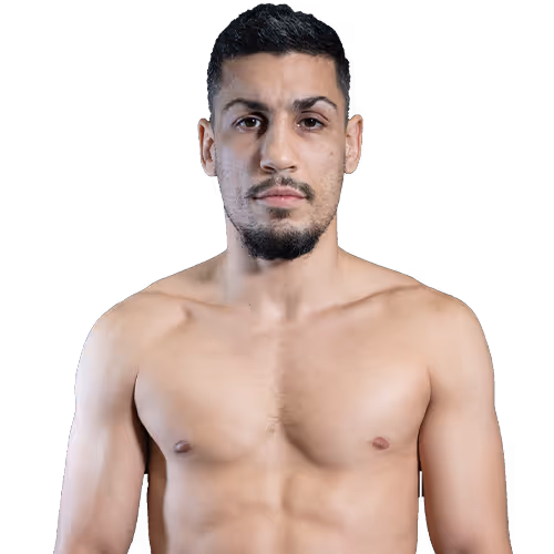 Muscular man with short dark hair and a beard, standing shirtless facing forward.