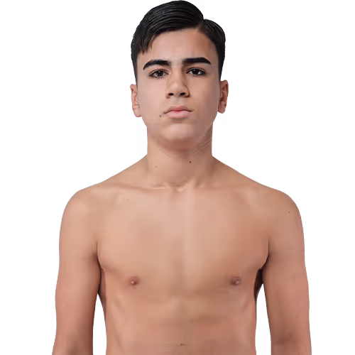 Young shirtless male with short dark hair looking straight ahead against a plain background.