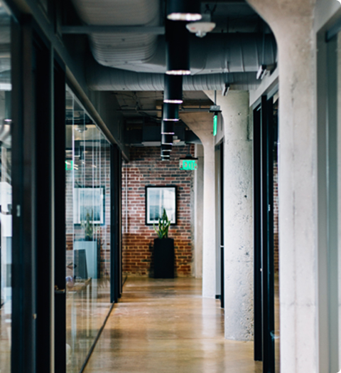 Hallway of a modern office with glass walls and exposed brick decor