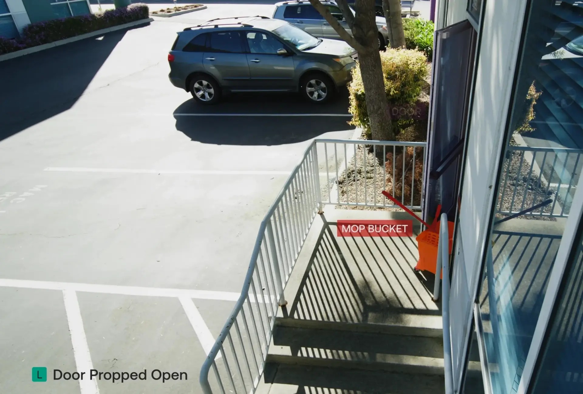 A security camera image of a door with a mop bucket propping it open.