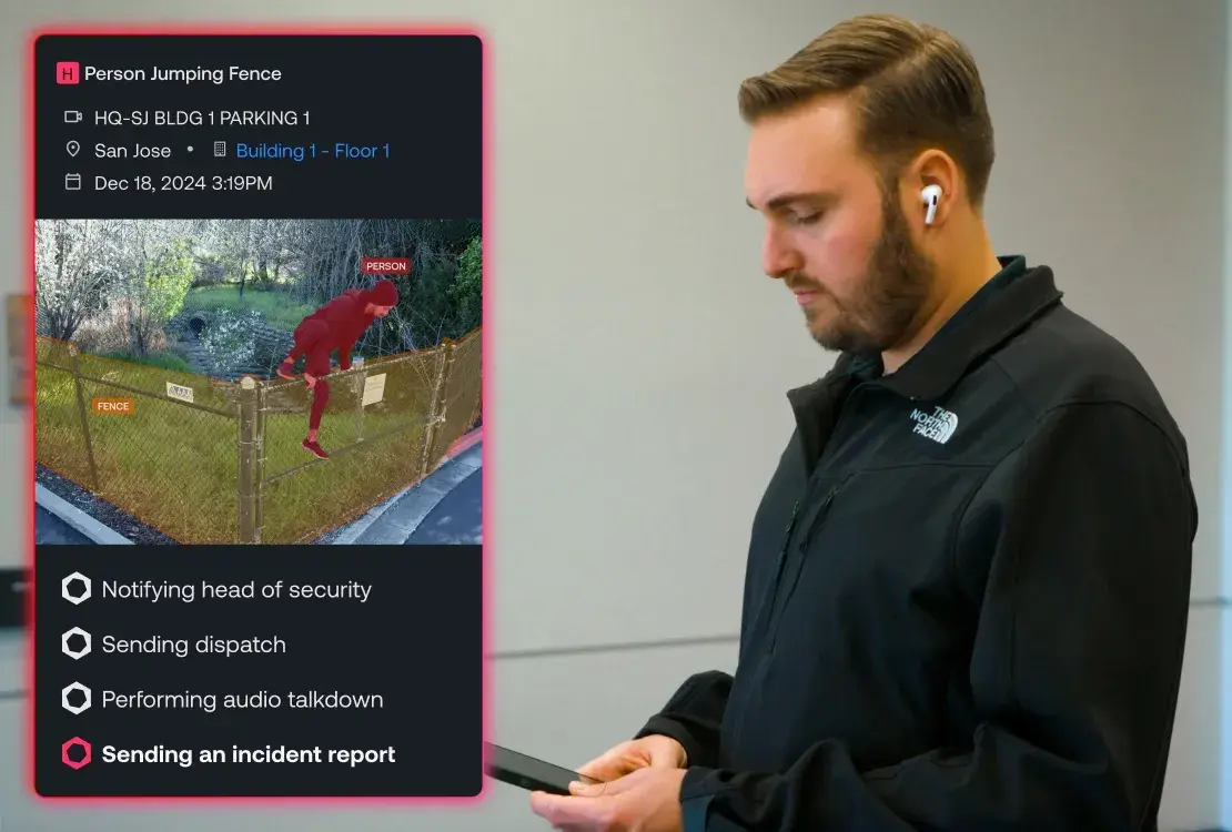 Man wearing a black North Face jacket and AirPods looks down at a tablet with a security alert overlay showing a person jumping a fence and incident response steps.