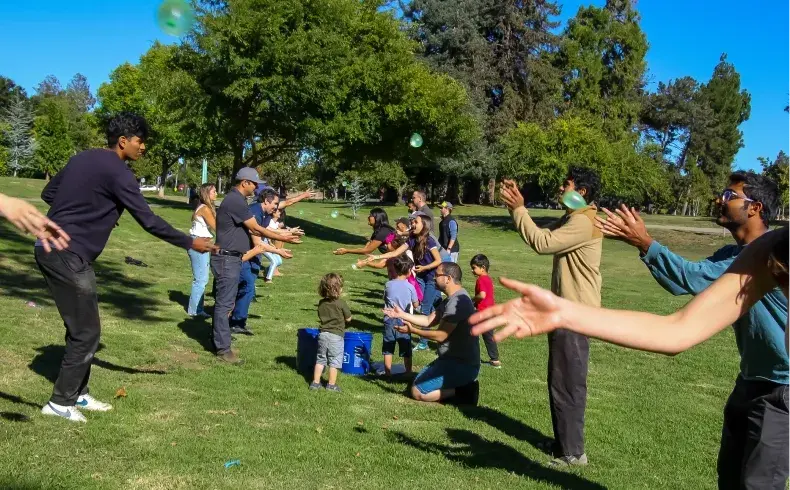 A group of people playing games on top of a lush green field.