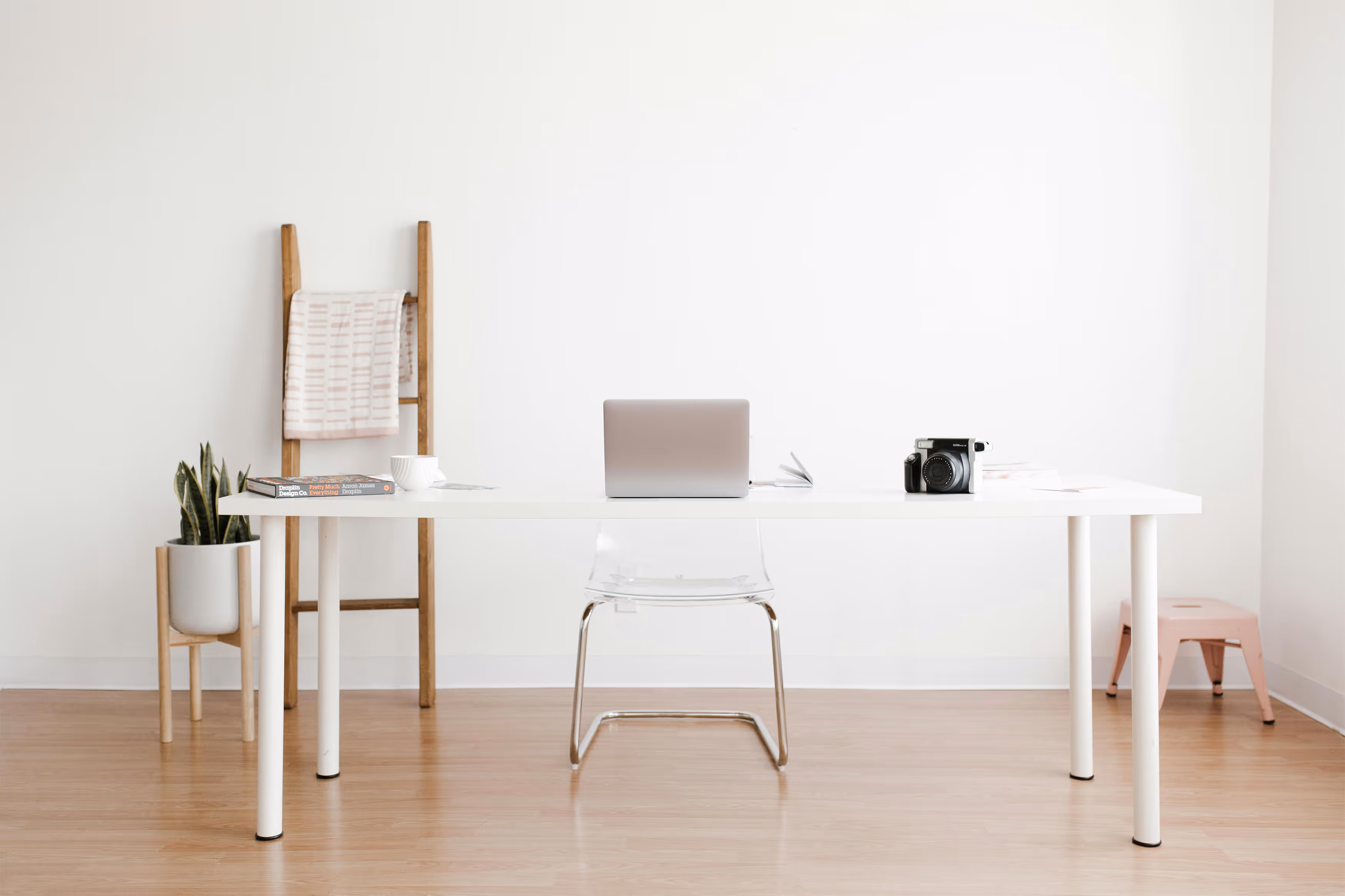 Minimalist workspace with laptop, camera, and white desk