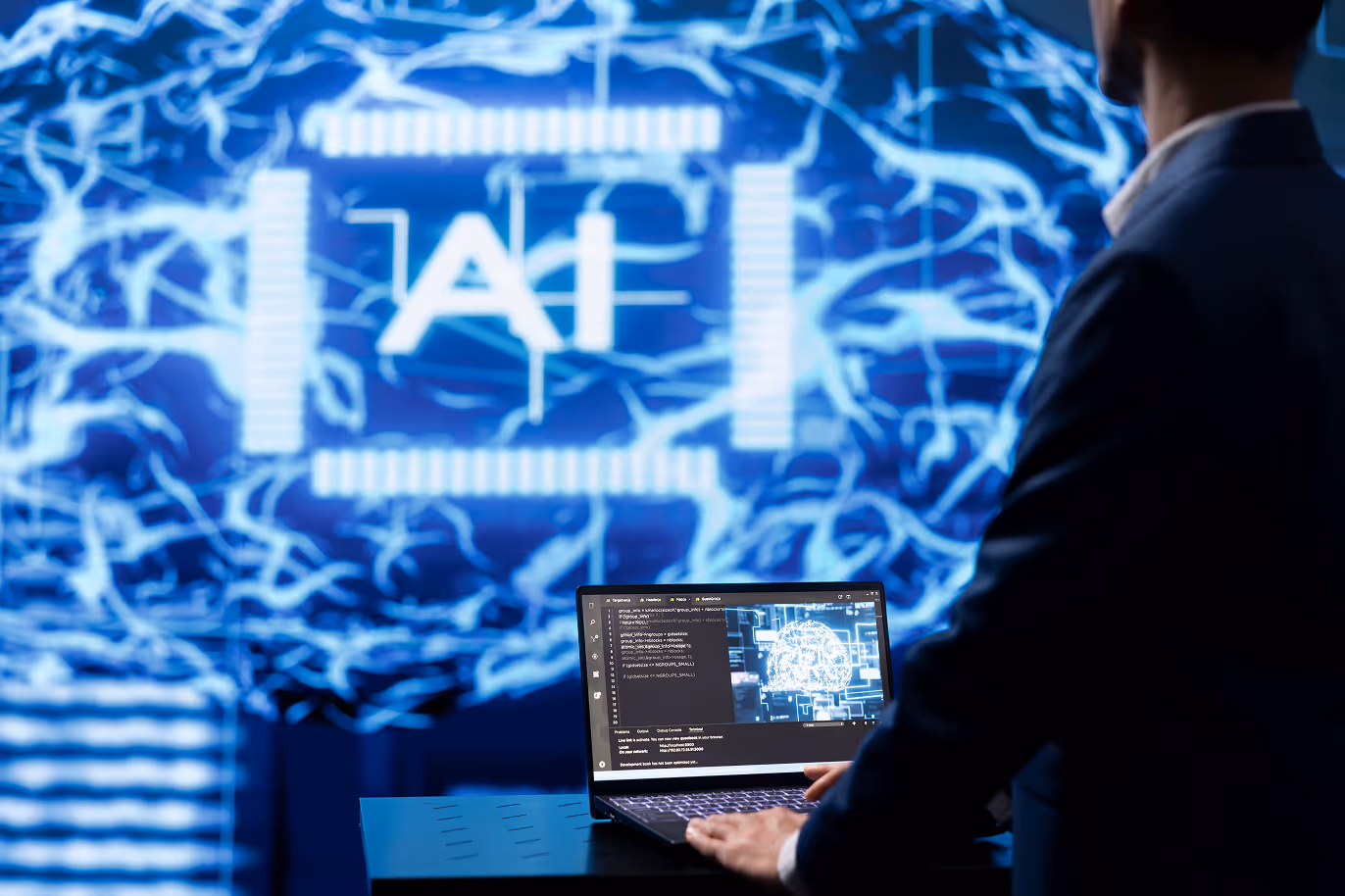 A man working on a laptop with an technical background that says "AI"