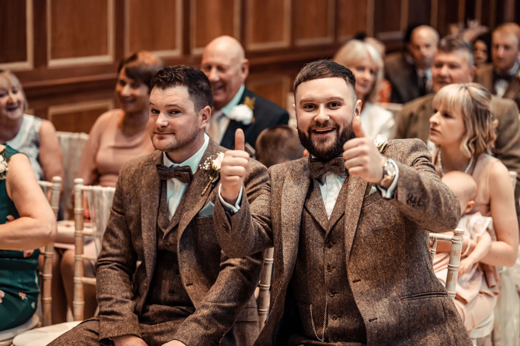 Two men in a wedding reception wearing bespoke lounge suits.