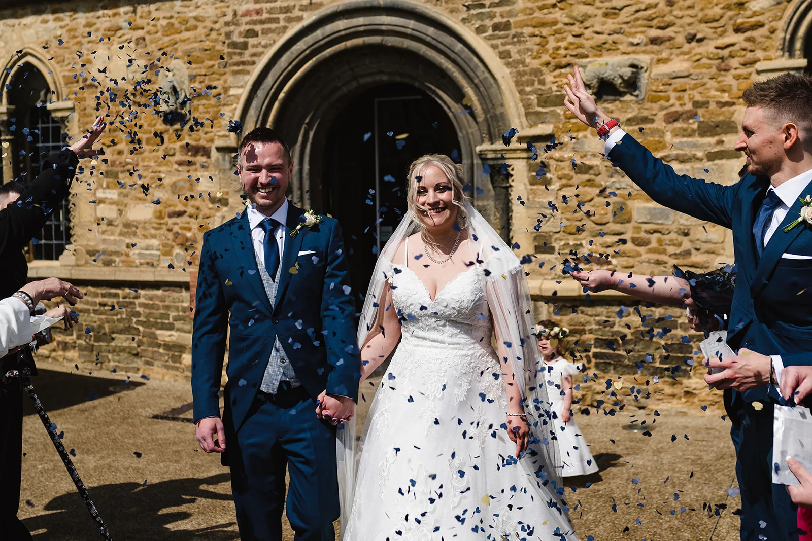 Married couple walking out of a church having confetti thrown over them. 