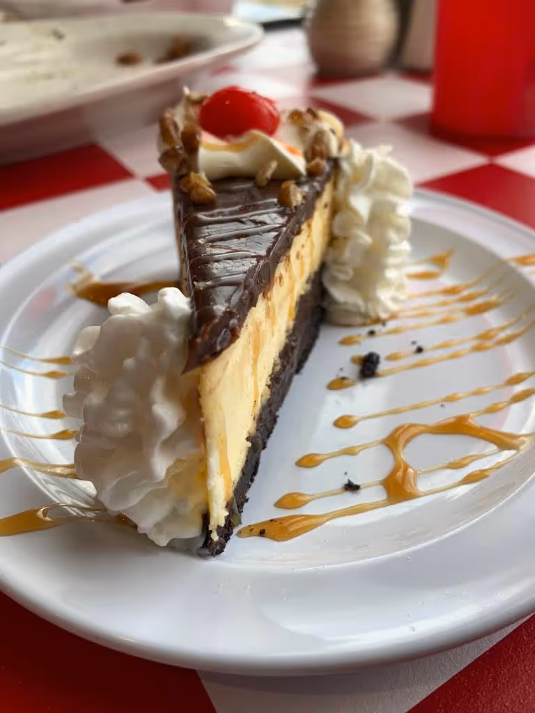 A slice of cake with whipped cream and a cherry on top.