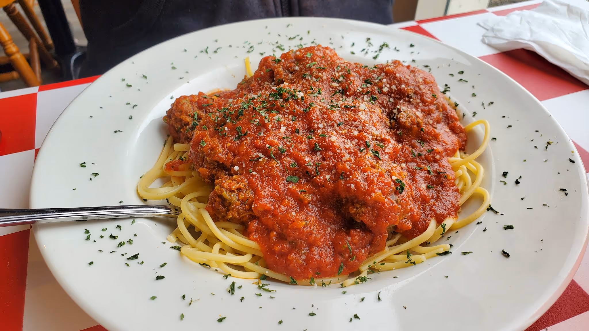 A plate of spaghetti with meat sauce and herbs.