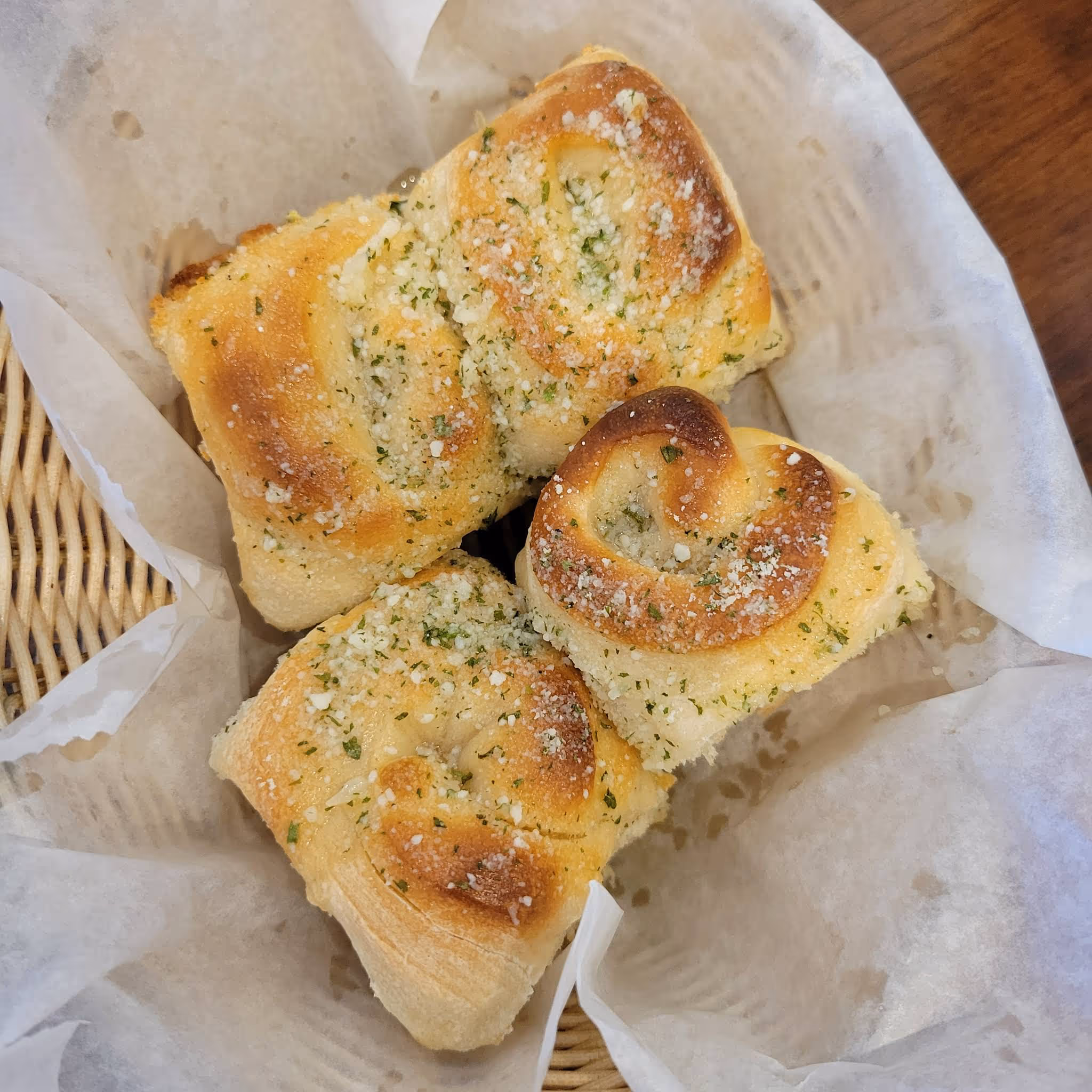 A basket of bread with seasoning on top.