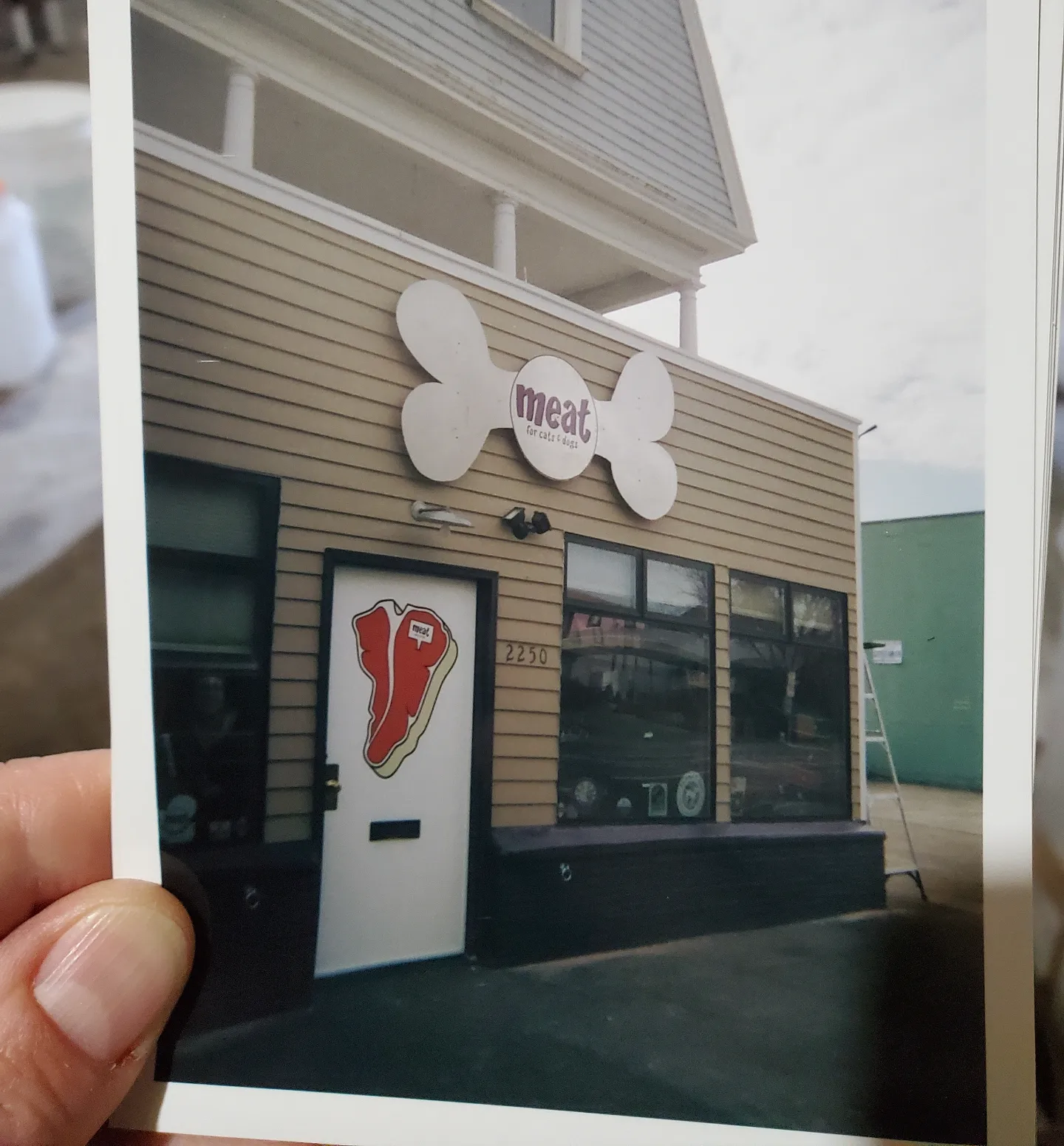 photo of someone holding a photo of Meat's old exterior of their store
