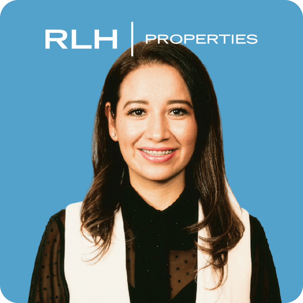 Smiling woman with long dark hair wearing braces, a black blouse with sheer sleeves, and a white vest, in front of a blue background with RLH Properties logo.