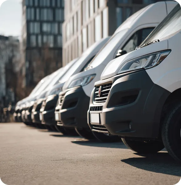 A row of white delivery vans parked side by side on a street in an urban area.