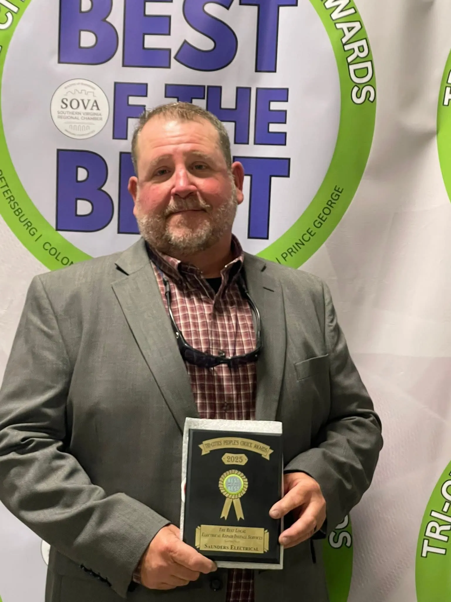Owner in gray blazer holding a 2025 Best Local Electrical Repair & Installation Services award plaque for Sanders Electrical.