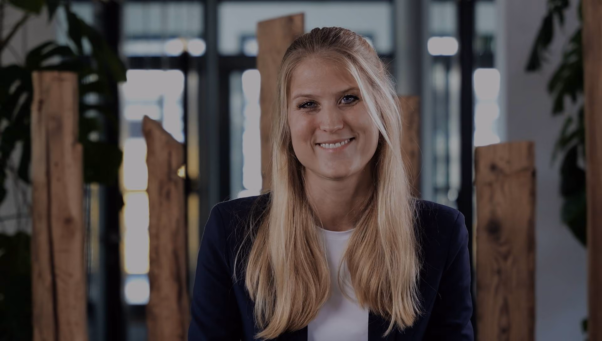 Frau vor Hintergrund mit Holzpfählen und Pflanzen - Bildmotiv für die Seite zum Leitbild bei Innovabee