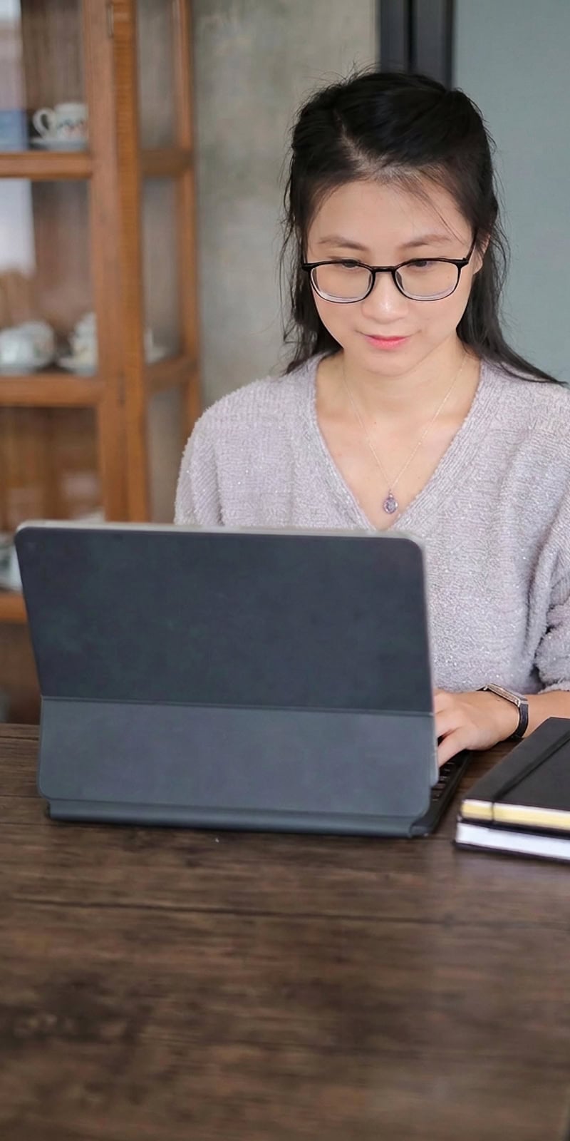 Woman in glasses working on a laptop at a desk