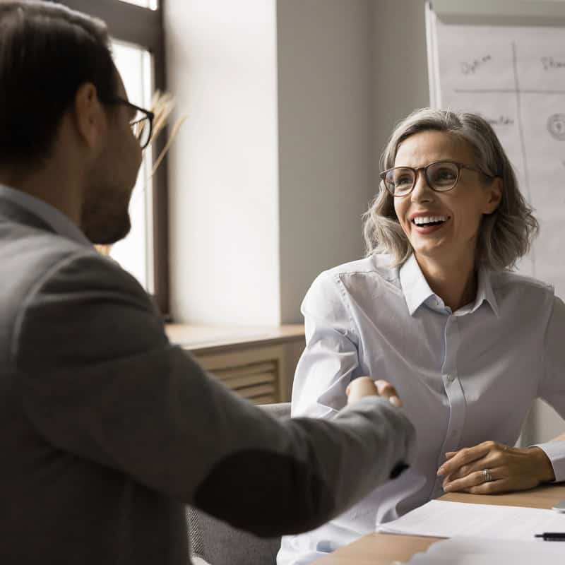 Hiring manager and candidate shaking hands after a successful job interview