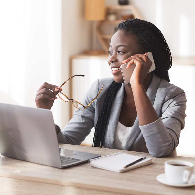 Smiling businesswoman talking on the phone while working at a laptop
