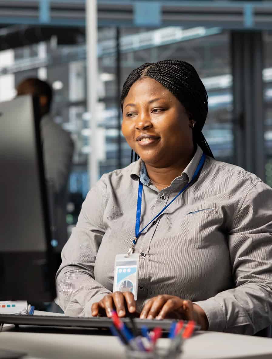 Focused employee wearing an ID badge working at a computer in an office