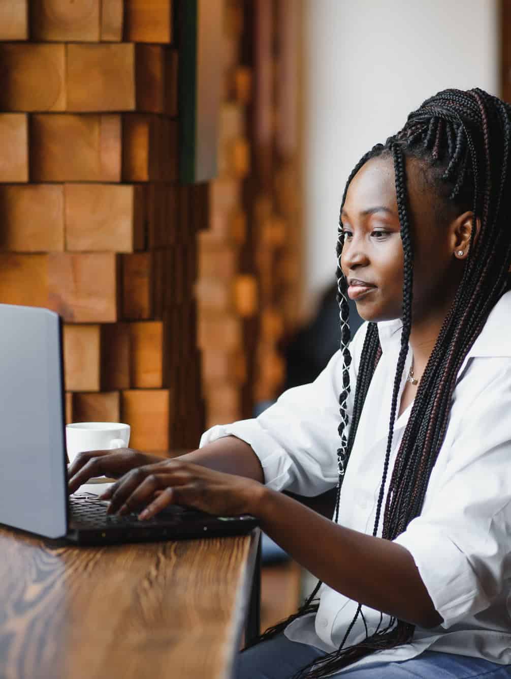 Young woman in a cafe focused on her laptop while searching for jobs online