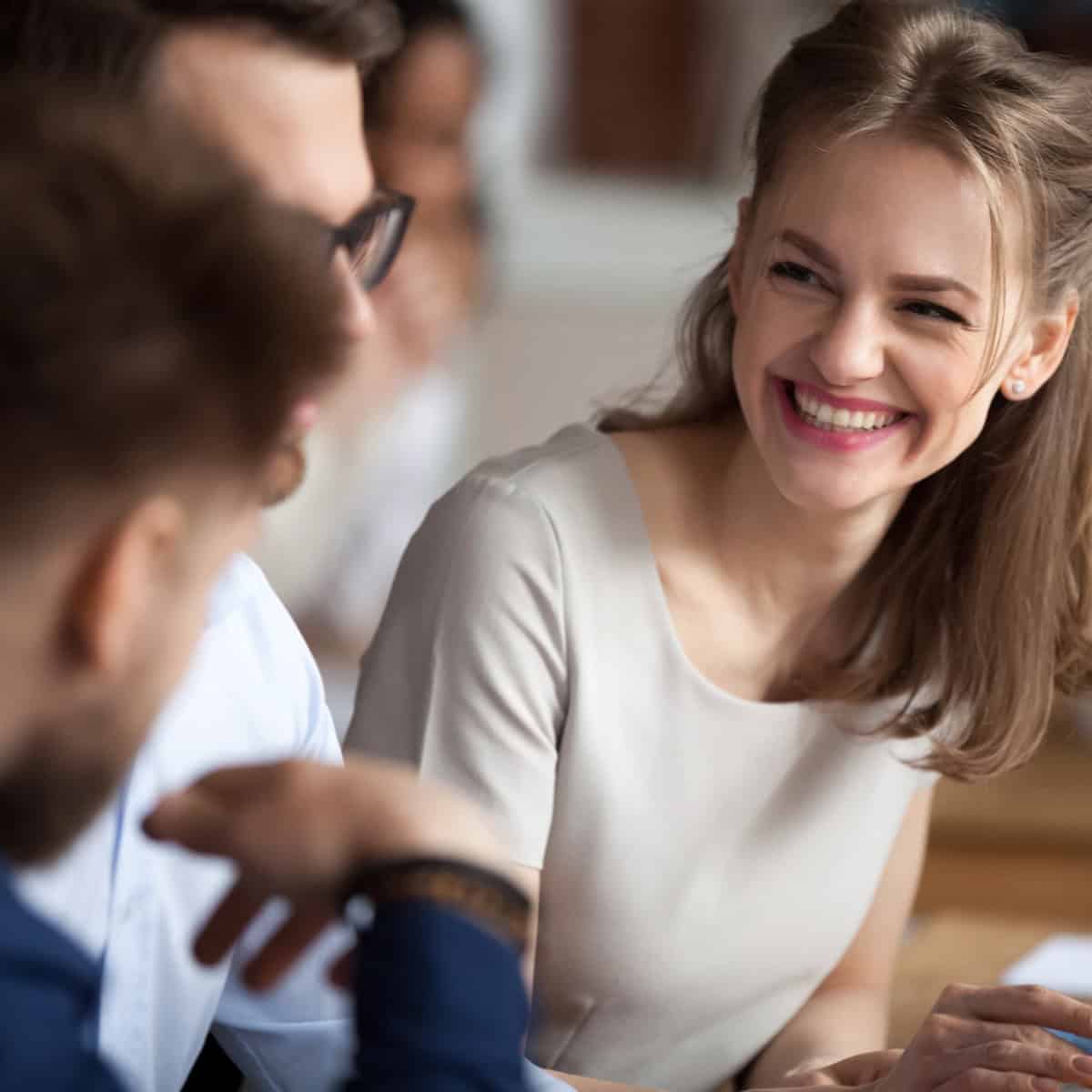 Smiling woman laughing with coworkers during a team meeting