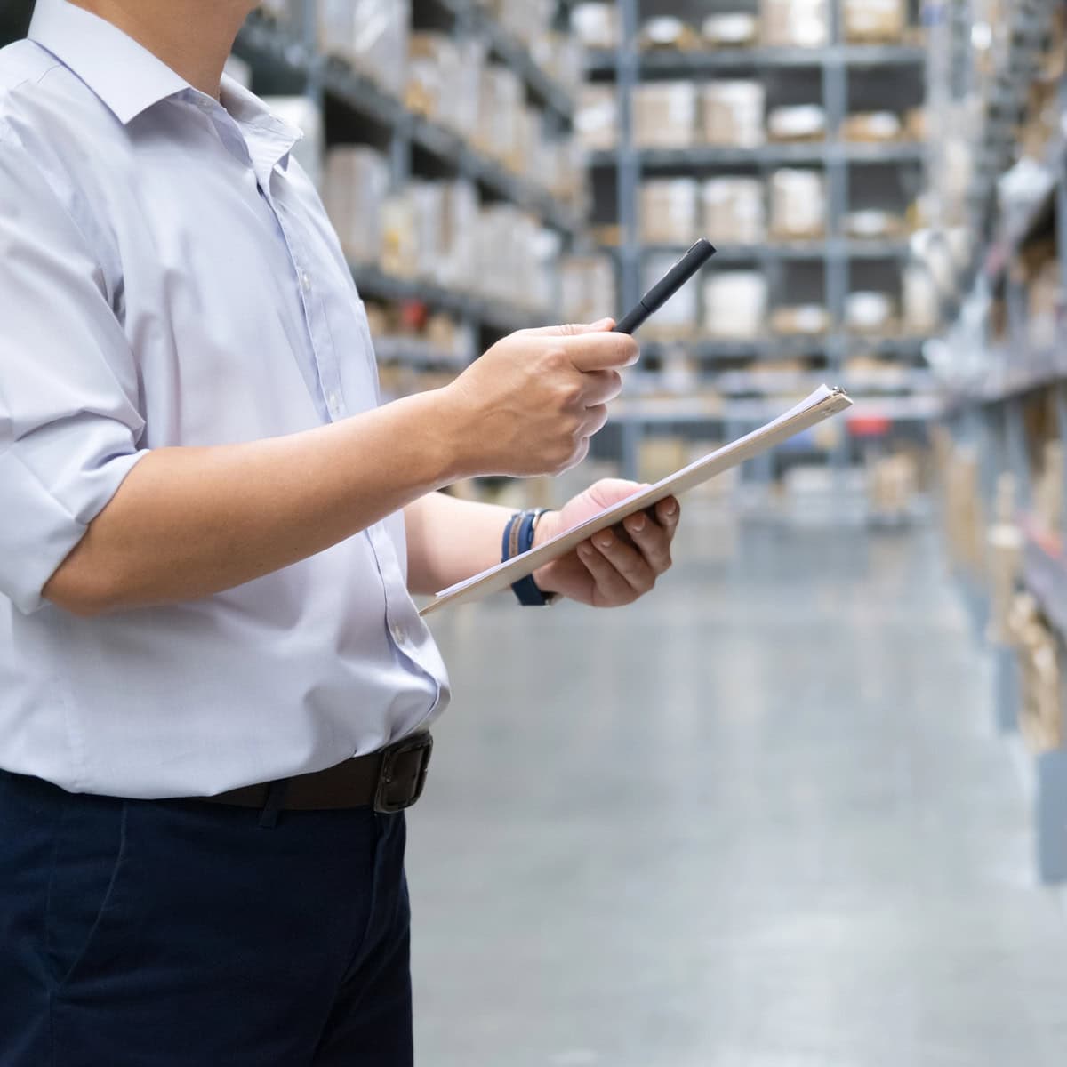 Warehouse manager checking stock levels and taking inventory among storage shelves